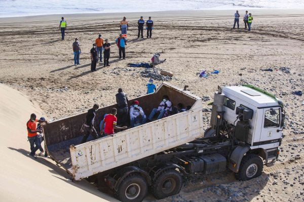 Would-be immigrants step into a truck on Maspalomas beach next to policemen on Gran Canaria in Spain's Canary Islands