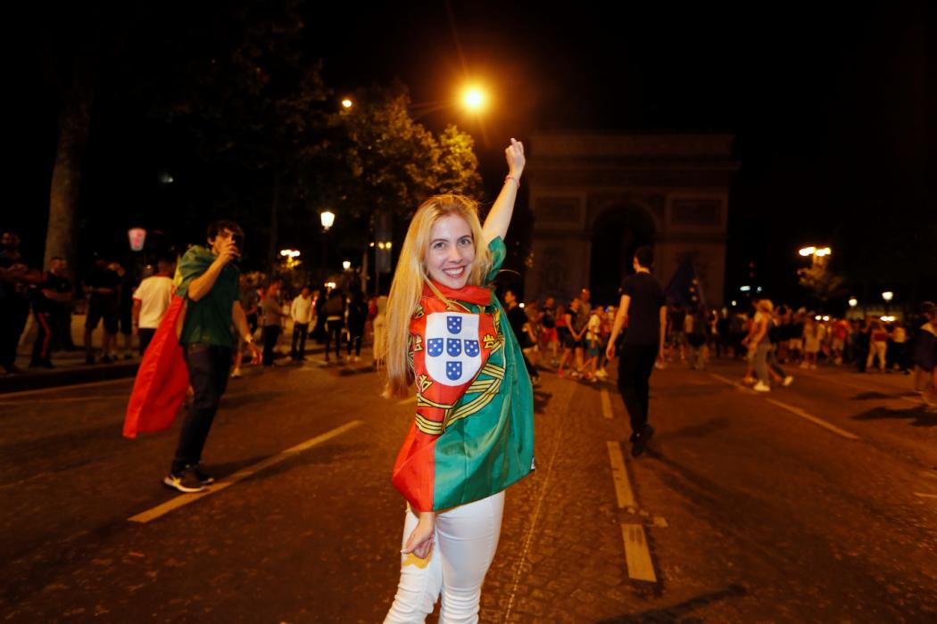 A Portugal supporter celebrates victory near the Arc de Triomphe after the Euro 2016 football tournament final match between Portugal and France on July 10, 2016 in Paris. / AFP PHOTO / Thomas SAMSON
