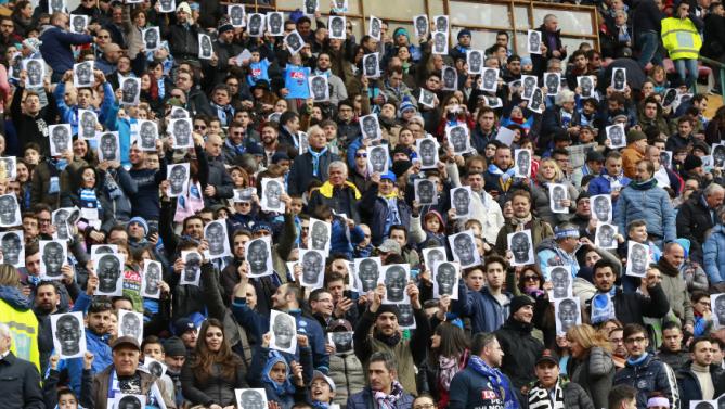 People hold flyers depicting the face of Napoli's French defender Kalidou Koulibaly before the Italian Serie A football match SSC Napoli vs Carpi FC on February 7, 2016 at the San Paolo stadium in Naples, in solidarity with the player victim of racists slogans from Lazio's fans during the football match SS Lazio vs SSC Napoli on February 3. / AFP / CARLO HERMANN