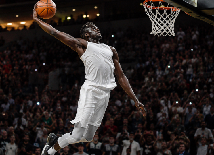 Joueur de basket en plein élan vers le panier pour un dunk.